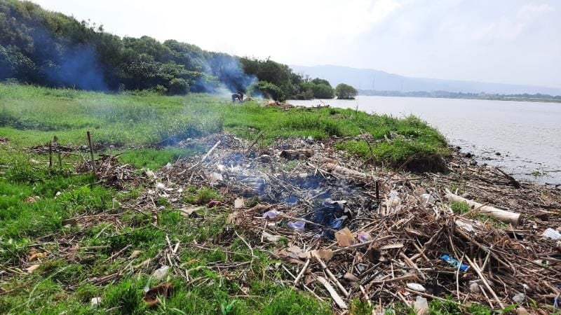 Warga membakar sejumlah sampah yang ada di sekitar tempat tambang pasir ilegal di Muara Sungai Opak, Bantul, Minggu (18/4/2021). [Muhammad Ilham Baktora / SuaraJogja.id]