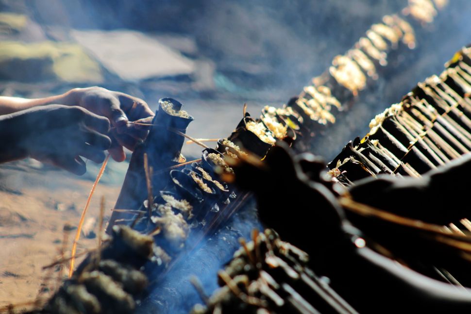 Pembuat nasi lemang memasukan daun pisang ke dalam bambu, di kawasan Senen, Jakarta Pusat, Senin (19/4/2021). [Suara.com/Dian Latifah]