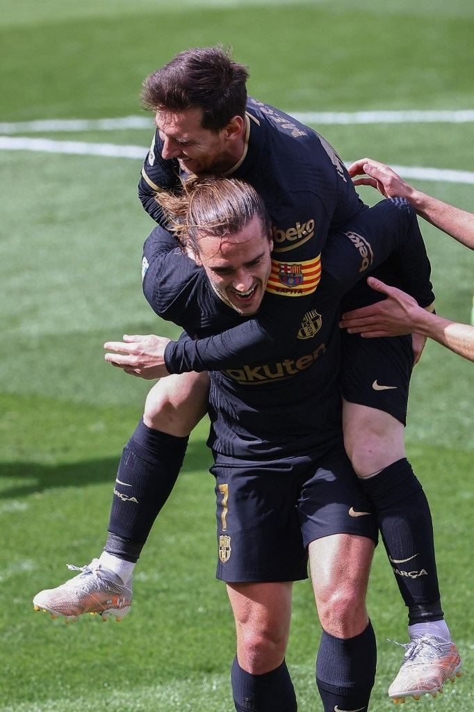 Penyerang Barcelona, Antoine Griezmann (bawah) merayakan golnya ke gawang Villarreal bersama penyerang Lionel Messi, pada laga Liga Spanyol 2020/2021 di Estadio de la Cerámica, Minggu (25/4/2021) malam WIB. [JOSE JORDAN / AFP]