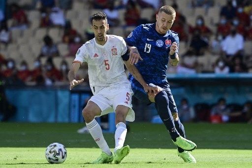 Gelandang Spanyol Sergio Busquets berebut bola dengan pemain Slovakia dalam pertandingan Grup E EURO 2020 di Stadion La Cartuja, Seville, Rabu (23/6). [AFP]