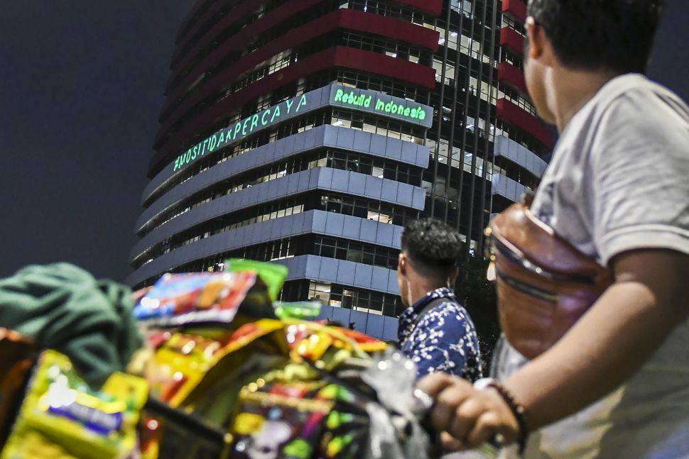 Pedagang menyaksikan proyeksi bertuliskan #mositidakpercaya saat aksi oleh aktivis Greenpeace di Gedung Merah Putih KPK, Jakarta, Senin (28/6/2021). [ANTARA FOTO/Galih Pradipta]