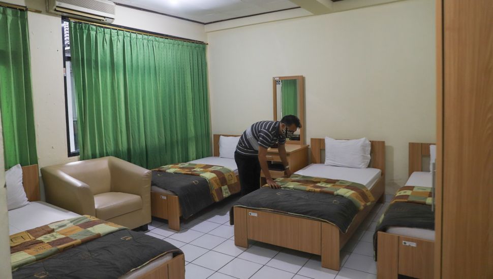 Petugas mempersiapkan kamar yang akan dipakai untuk tempat isolasi mandiri di Asrama Haji Pondok Gede, Jakarta Timur, Selasa (29/6/2021). [Suara.com/Alfian Winanto]
