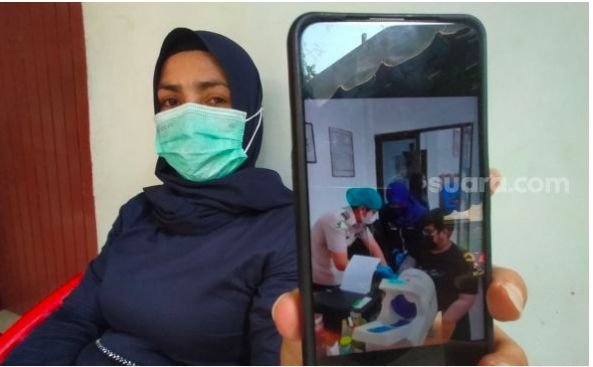 Ibu korban menunjukkan foto anaknya saat diperiksa hendak divaksin Covid-19. [Suara.com/M.Aribowo]