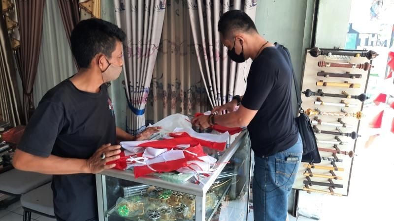 Pedagang Bendera Merah Putih, Endang melayani pembeli di tokonya Jalan Wonosari, Kalurahan Tegaltandan, Kapanewon Banguntapan, Kabupaten Bantul, Senin (16/8/2021). [Muhammad Ilham Baktora / SuaraJogja.id]