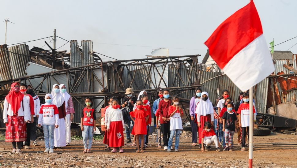 Anak-anak dari Komunitas Kelas Jurnalis Cilik melakukan upacara bendera HUT RI ke-76 di Belah Kapal, Cilincing, Jakarta Utara, Selasa (17/8/2021). [Suara.com/Alfian Winanto]