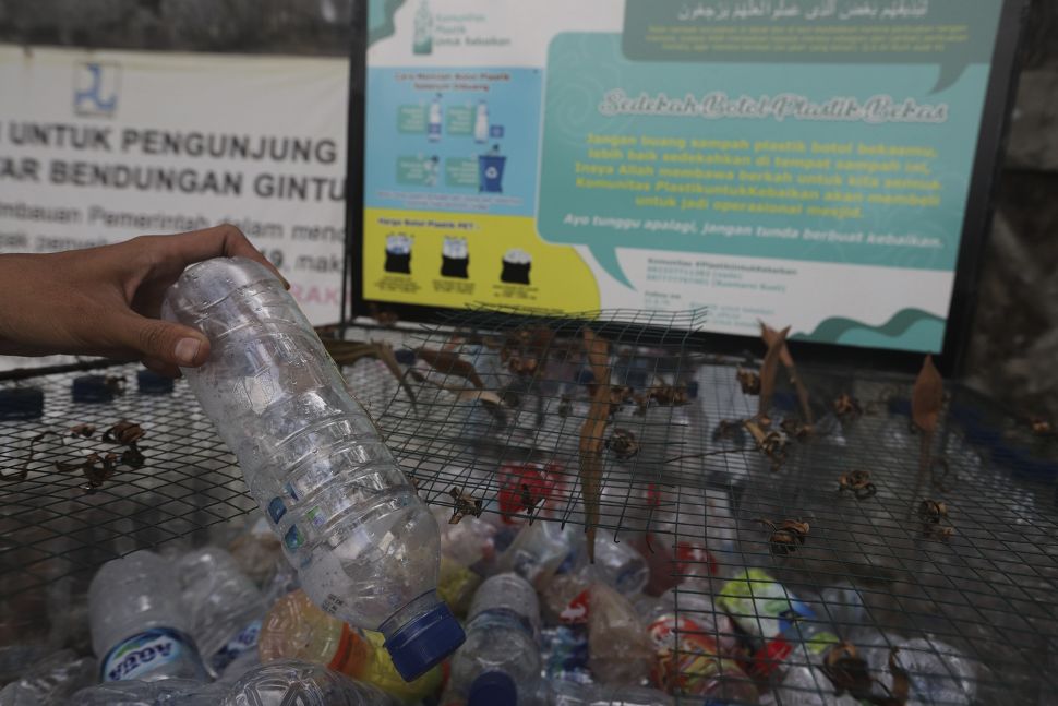Pengunjung memasukkan sampah botol ke dalam tempat sampah yang berada di kawasan Situ Gintung, Tangerang Selatan, Banten, Kamis (9/9/2021). [Suara.com/Angga Budhiyanto]