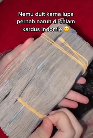 Wanita bongkar uang yang dibungkus plastik di kardus. (Tiktok)