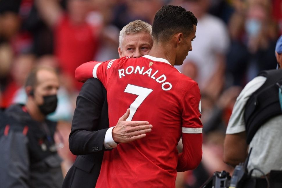 Megabintang Manchester United, Cristiano Ronaldo (kanan) berpelukan dengan sang pelatih, Ole Gunnar Solskjaer seusai laga Liga Inggris kontra Newcastle United di Old Trafford, Manchester, Sabtu (11/9/2021) malam WIB. [OLI SCARFF / AFP]