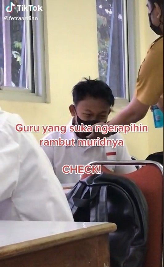 Tak seperti biasanya, seorang guru tampak merapikan rambut muridnya setelah mendapati dalam keadaan gondrong. [TikTok]