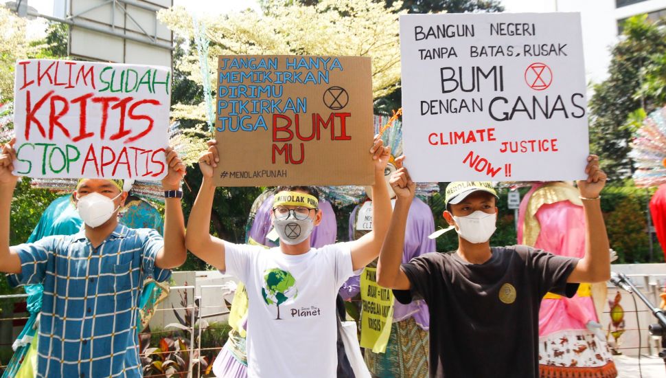 Sejumlah aktivis menunjukkan poster saat melakukan aksi protes terkait perubahan iklim di Kawasan Dukuh Atas, Jakarta Pusat, Minggu (26/9/2021). [Suara.com/Alfian Winanto]