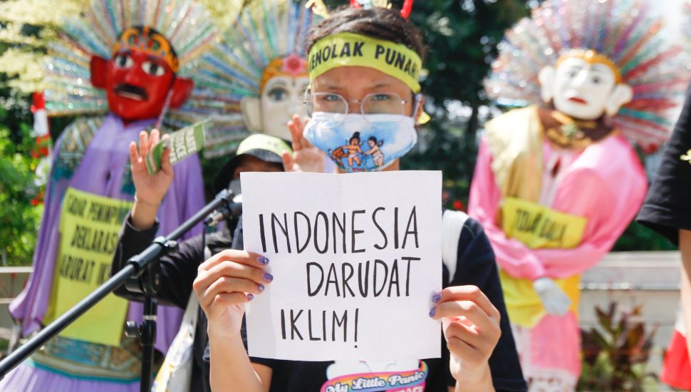 Seorang aktivis menunjukkan poster saat melakukan aksi protes terkait perubahan iklim di Kawasan Dukuh Atas, Jakarta Pusat, Minggu (26/9/2021). [Suara.com/Alfian Winanto]