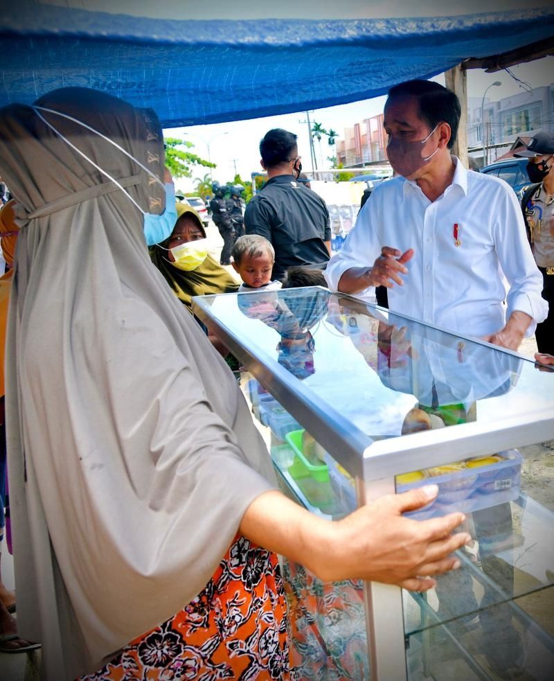 Presiden menyambangi ibu-ibu yang membentangkan tulisan saat rombongannya melintas di Jalan Basuki Rahmat Kota Sorong, Papua pada Senin (4/10/2021). [BPM Setpres]