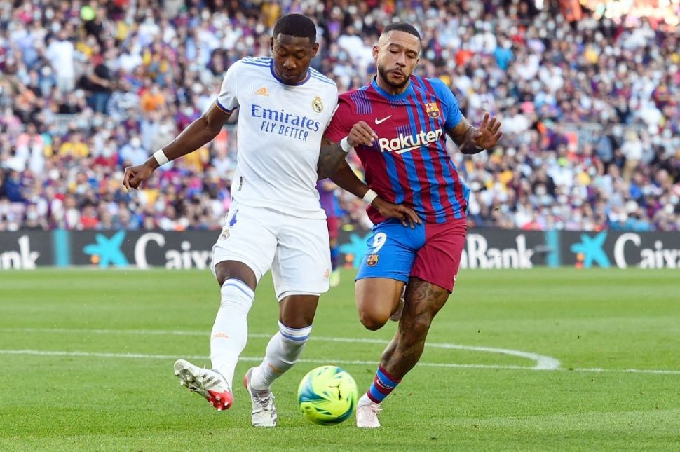 Bek Real Madrid, David Alaba berebut bola dengan penyerang Barcelona, Memphis Depay dalam laga Liga Spanyol di Camp Nou, Barcelona, Minggu (24/10/2021) malam WIB. [Josep LAGO / AFP]