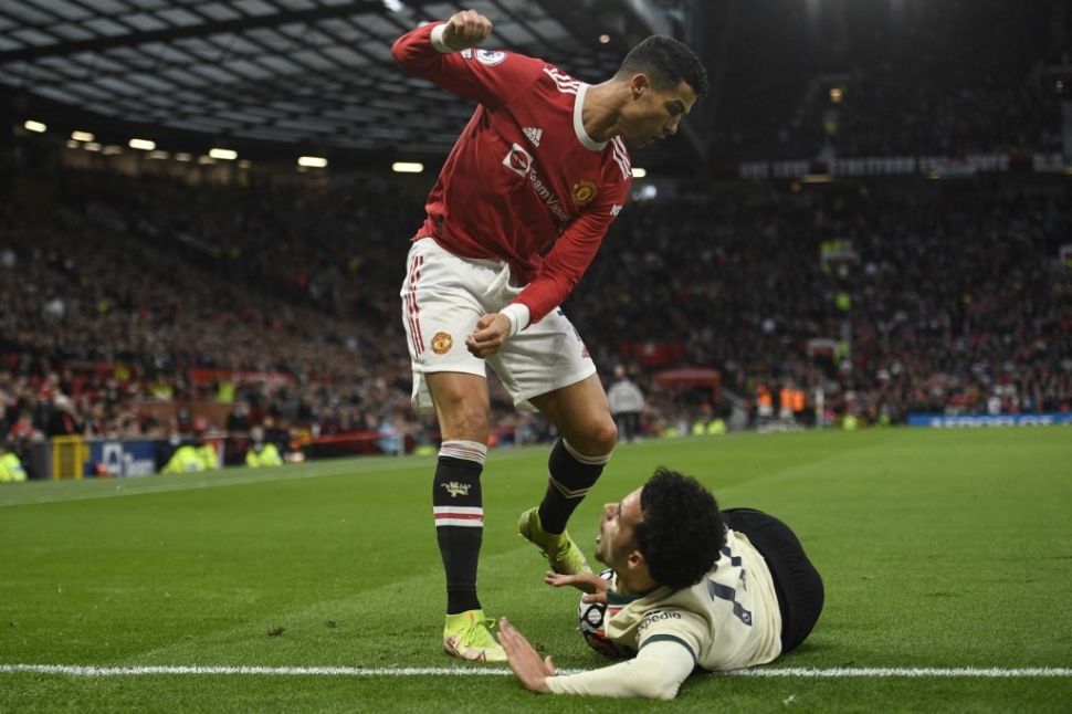 Penyerang Manchester United, Cristiano Ronaldo (kiri) menendang bola yang tengah berada di antara paha dan perut gelandang Liverpool, Curtis Jones dalam matchday kesembilan Liga Inggris, di Old Trafford, Minggu (25/10/2021) malam WIB. [AFP].