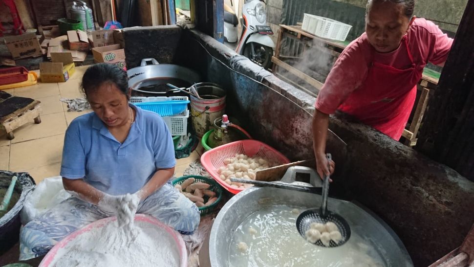 Pekerja memasak pempek di dapur Minah [Suara.com/Tasmalinda]