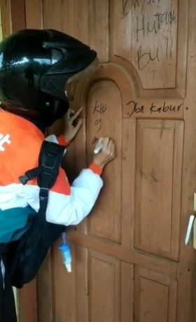 Wanita mencorat-coret pintu rumah nasabah untuk menagih utang. (Tiktok)