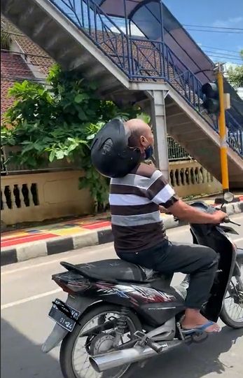 Helm pengendara motor tersangkut di leher. (Tiktok/@noisyboyyyyyyyy)