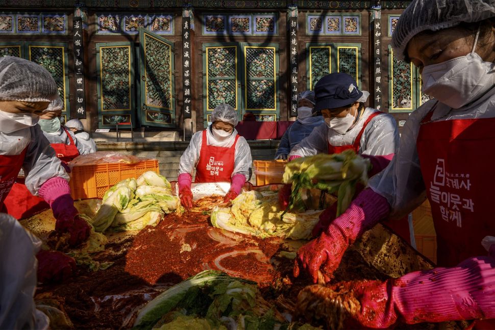 Para peserta menyiapkan kimchi, hidangan tradisional Korea dari kubis dan lobak pedas yang difermentasi, selama festival pembuatan kimchi di kuil Buddha Jogyesa, Seoul, Korea Selatan, pada (2/12/2021). [ANTHONY WALLACE / AFP]