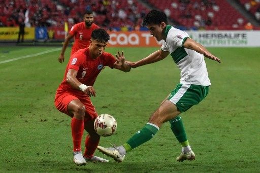 Pemain Singapura Ikhsan Fandi (kiri) berebut bola dengan pemain Indonesia Elkan Baggott dalam pertandingan leg pertama semifinal Piala AFF 2020 di Stadion Nasional, Rabu (22/12/2021). [AFP]