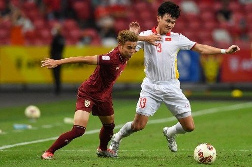 Pemain Thailand Theerathon Bunmathan (kiri) berebut bola dengan pemain Vietnam di leg kedua semifinal Piala AFF 2020 di Stadion Nasional, Singapura, Minggu (26/12/2021). [AFP]