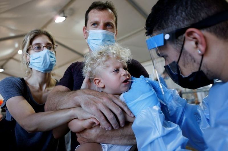 Seorang petugas kesehatan melakukan test Covid-19 kepada seorang anak balita di Tel Aviv, Israel, 8 Juli 2021. (Antara/Reuters)