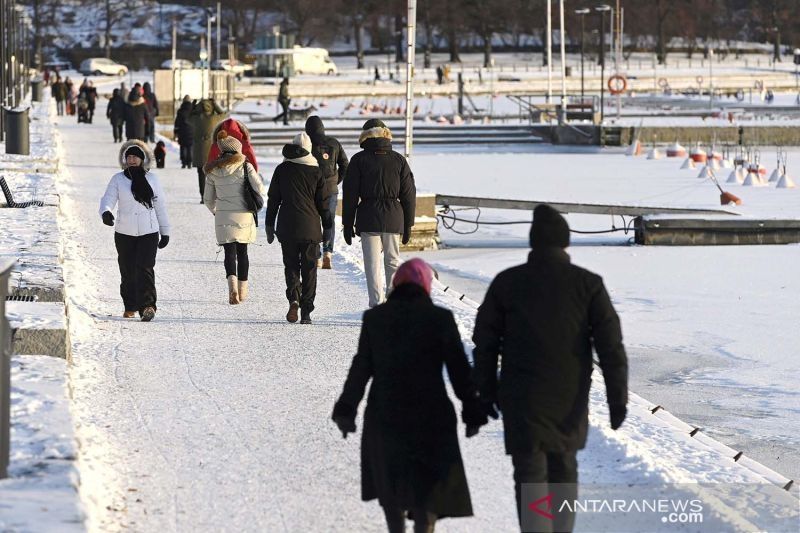 Warga berjalan di tepi laut di hari yang cerah tapi membekukan pada Boxing Day di Helsinki, Finlandia, Minggu (26/12/2021). ANTARA FOTO/Lehtikuva/Heikki Saukkomaa via REUTERS/AWW/djo