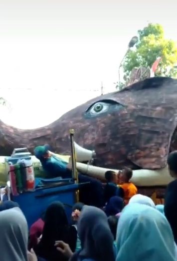Momen tak terduga seorang penjual minuman yang berdiri di pinggir jalan tertubruk parade patung gajah. (TikTok/triya_tiknaa)