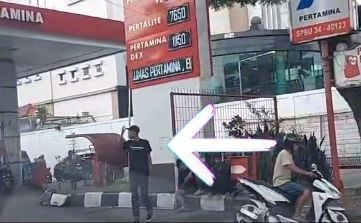 Seorang pria meniup peluit di tikungan pom bensin yang diduga sebagai juru parkir. (TikTok/anti.jukir)