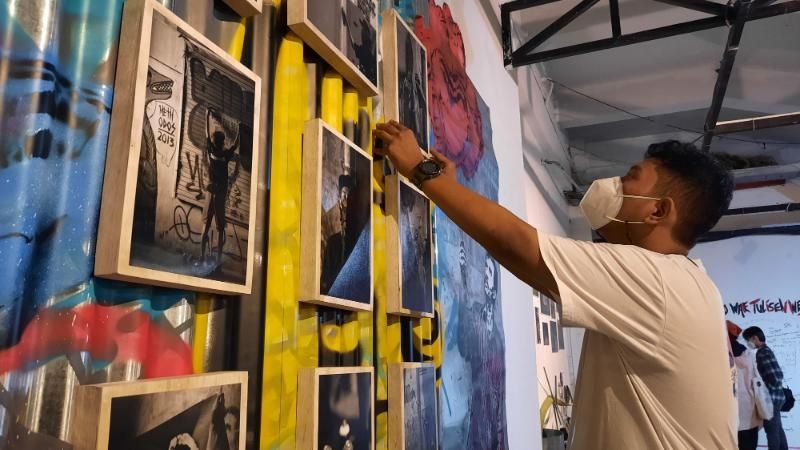 Mahasiswa Fotografi 2019, ISI Yogyakarta, Didan Nur Fisyanuari Rosadi merapikan bingkai foto miliknya saat pameran Artsay di Taman Budaya Yogyakarta (TBY), Sabtu (5/3/2022). [Muhammad Ilham Baktora / SuaraJogja.id]