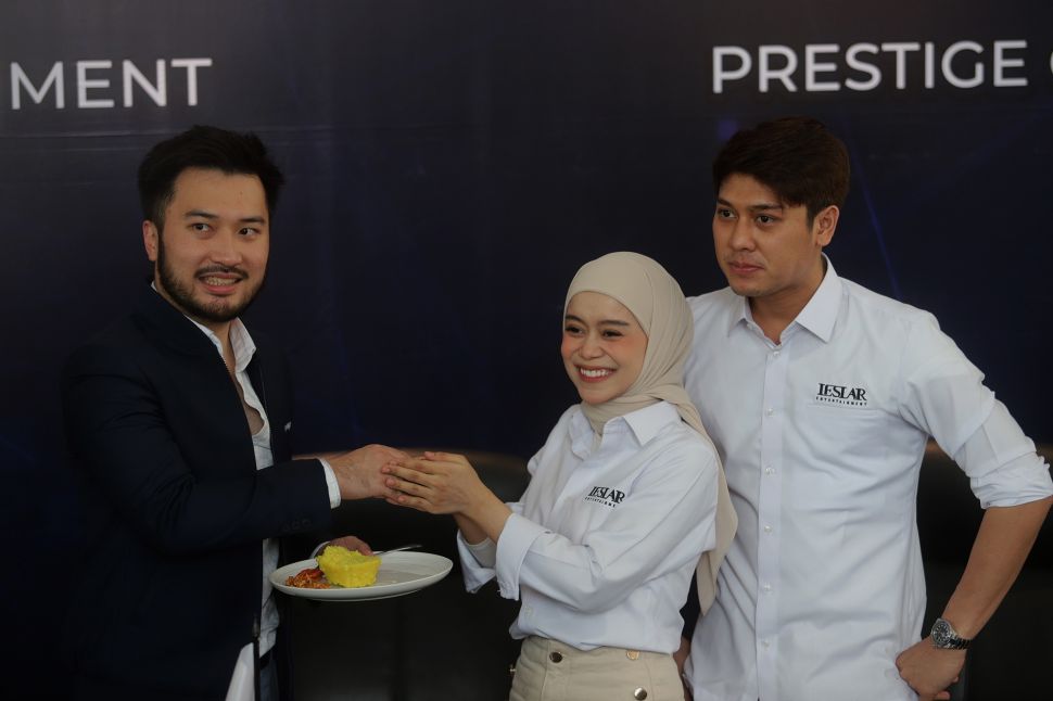 Presiden Direktur Prestige Motorcars Rudy Salim (kiri) menerima potongan tumpeng dari Pendiri Leslar Entertainment Lesti Kejora (tengah) usai menandatangani akuisisi Leslar Entertainment oleh Prestige Corp di Prestige Image Corp, Pluit, Jakarta, Jumat (11/3/2022). [Suara.com/Angga Budhiyanto]