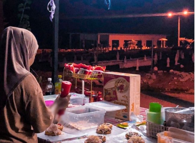 Penampakan warung gadis yang berjualan di depan sebuah arena pemakaman saat malam hari. (Mstar)