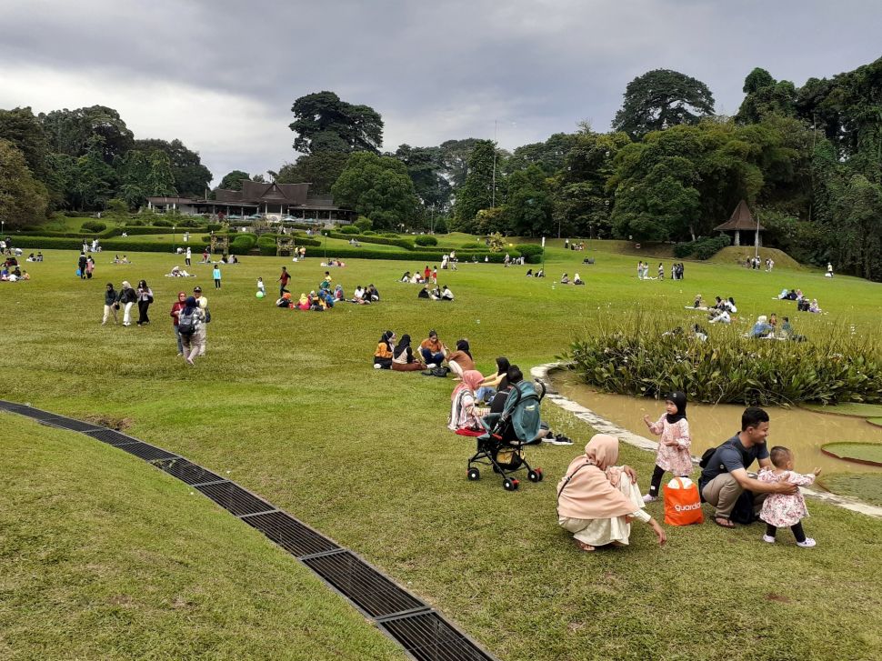 Suasana pengunjung piknik di halaman Kebun Raya Bogor, Bogor ,jawa Barat, Minggu (27/3/2022).  [Suara.com/Septian]