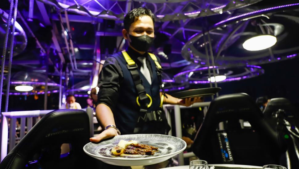 Pelayan menyajikan makan malam diatas ketinggian 50 meter di restoran Lounge In The Sky Indonesia di Setiabudi, Jakarta Selatan, Selasa (29/3/2022). [Suara.com/Alfian Winanto]