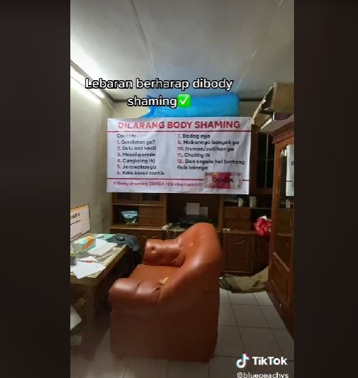 seorang warga memasang banner dilarang body shaming bagi keluarga yang berkunjung saat lebaran. [bluepeachys / TikTok]