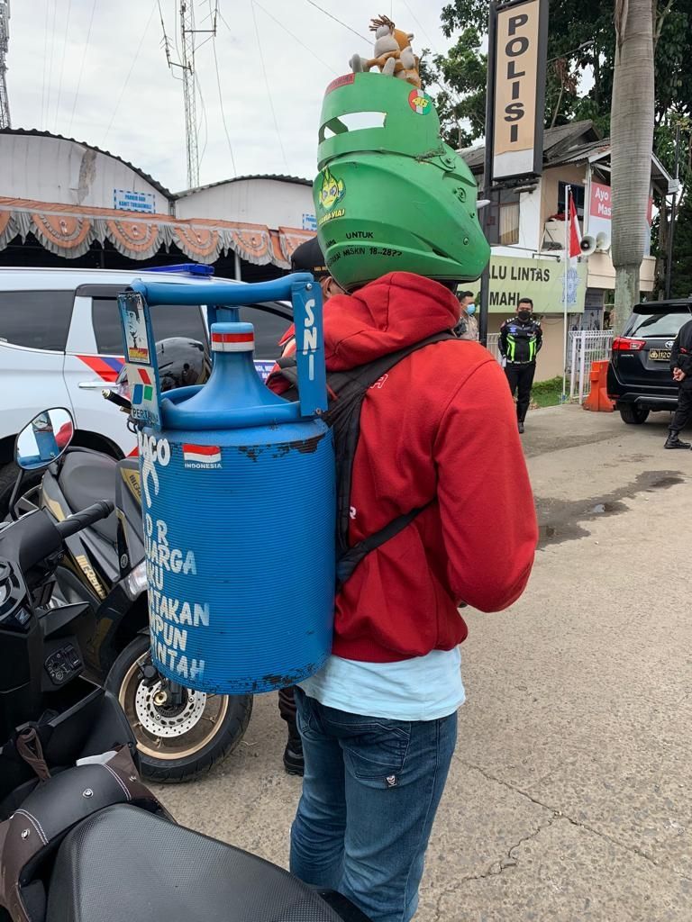 Depan, Pemudik Nyentrik dengan tas dan helm menyerupai tabung gas elpiji yang melintas di Kawasan Padalarang Kabupaten Bandung Barat (KBB). [SuaraJabar/Ferry Bangkit]