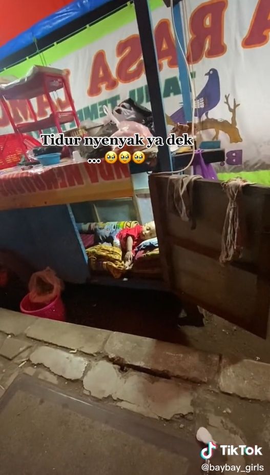 Seorang bayi yang ikut ayahnya berdagang pecel lele hingga tengah malam terpaksa tidur di dalam gerobak. [TikTok/@baybaygirls]