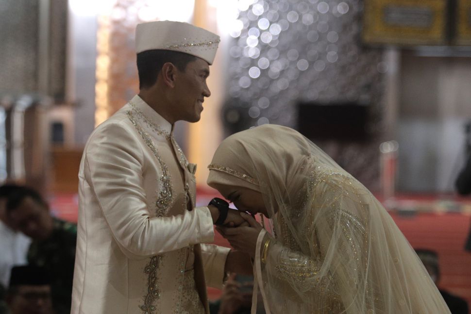 Artis Juliana Moechtar meencium tangan suaminya, Letkol Inf Nur Wahyudi saat akad nikah di Masjid Istiqlal, Jakarta, Jumat (27/5/2022). [Suara.com/Angga Budhiyanto]