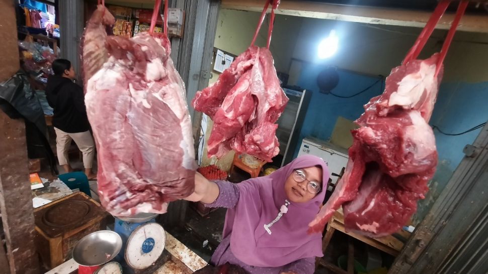 Pedagang daging sapi di Pasar Rakyat Jongkat, Kabupaten Mempawah, Kalimantan Barat memperlihatkan daging sapi yang akan dijual untuk pelanggan. [Suara.com/Diko Eno]