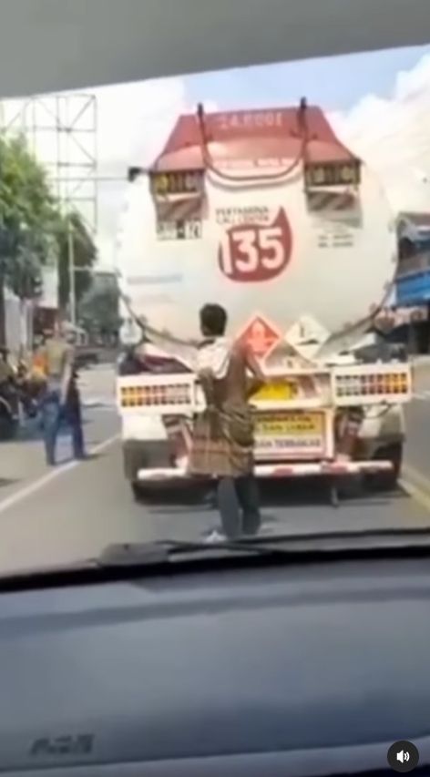 Orang dengan gangguan kejiwaan atau ODGJ terekam video bergelantungan di belakang truk tangki BBM yang sedang berjalan. [Instagram]