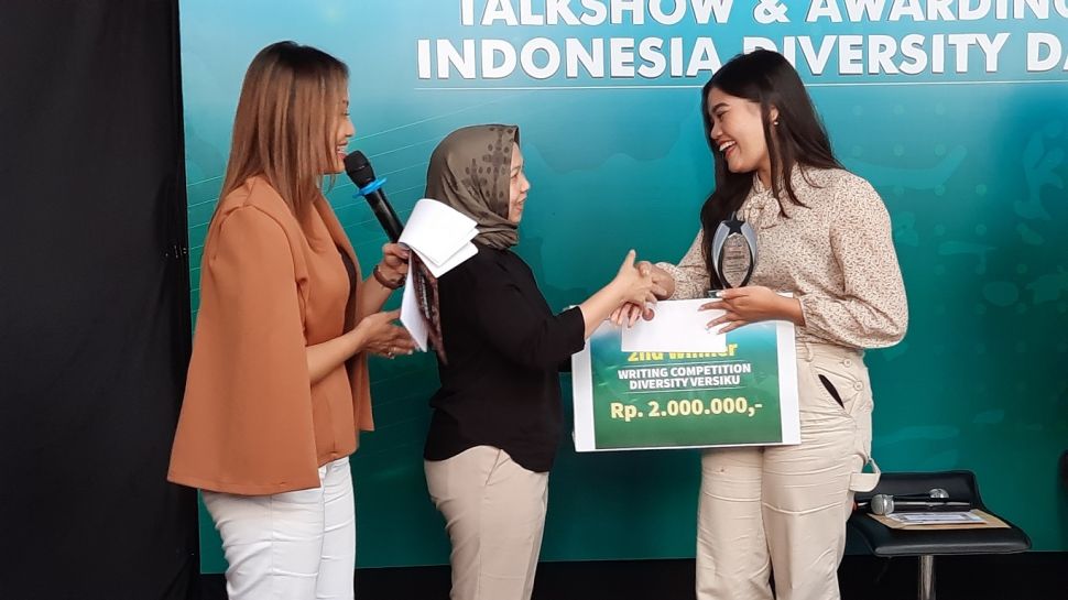 Country manajer International Media Support (IMS), Eva Danayanti (baju hitam) memberikan hadiah kepada Maria Anggraeni Rahmawati sebagai juara 2 dalam kompetisi menulis Diversity Versiku di Kantor Suarajogja.id, Sleman, DIY, Senin (20/6/2022). [Muhammad Ilham Baktora/Suarajogja.id]