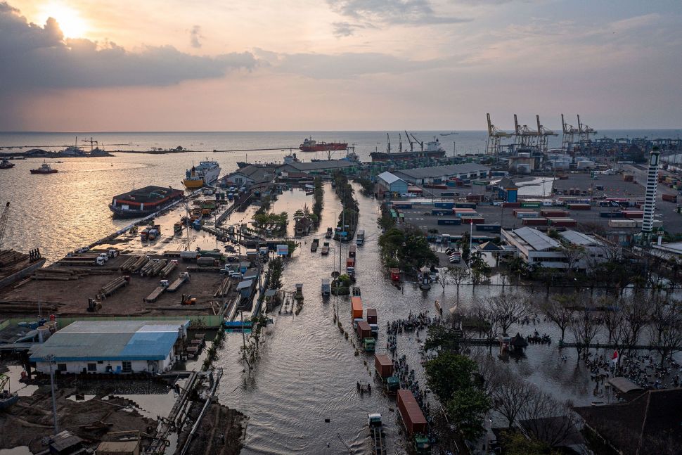 Foto udara ratusan pekerja industri kawasan pelabuhan berjalan menembus banjir limpasan air laut ke daratan atau rob yang merendam kawasan Pelabuhan Tanjung Emas Semarang, Jawa Tengah, Senin (20/6/2022).  ANTARA FOTO/Aji Styawan