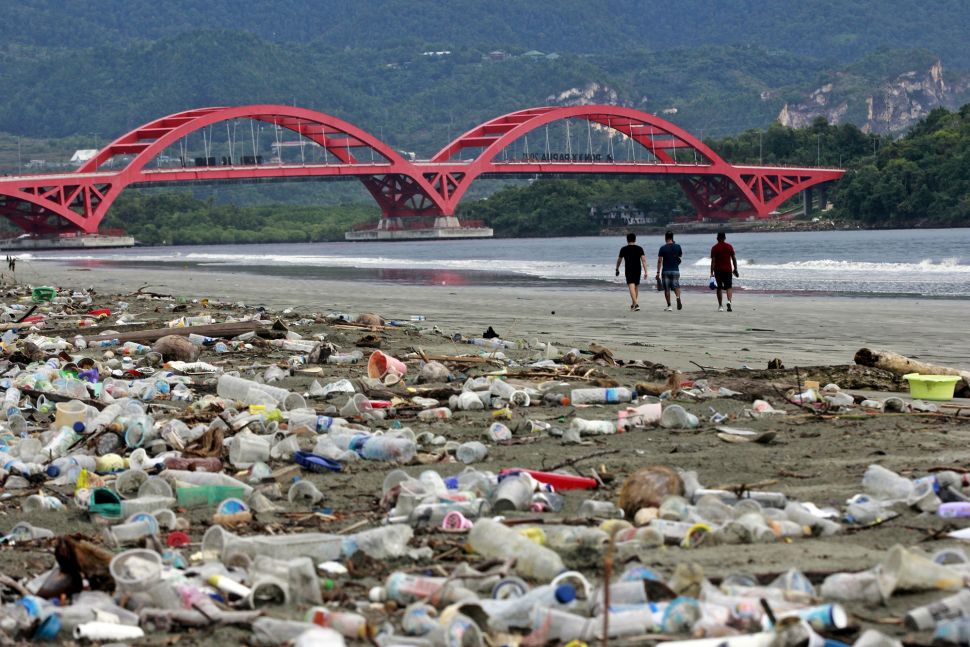 Sejumlah warga melintas di dekat sampah-sampah plastik di pesisir Teluk Youtefa, Jayapura, Papua, Sabtu (23/7/2022).  ANTARA FOTO/Gusti Tanati