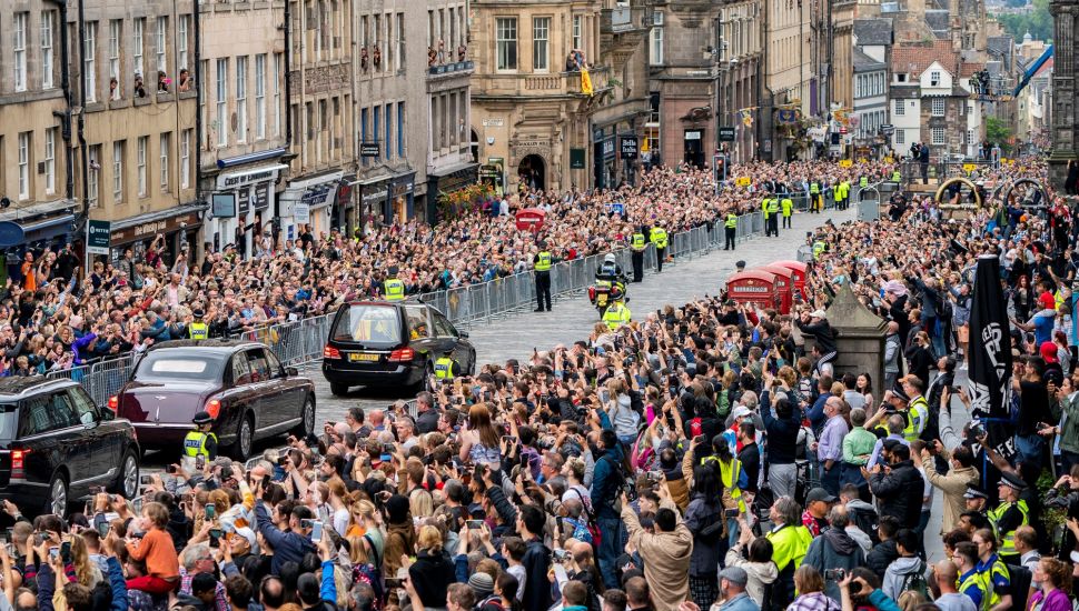 Masyarakat berkumpul di sepanjang Royal Mile untuk menyaksikan mobil jenazah yang membawa peti mati Ratu Elizabeth II menuju Istana Holyroodhouse, Edinburgh, Skotlandia, Minggu (11/9/2022). [Jane Barlow / POOL / AFP]