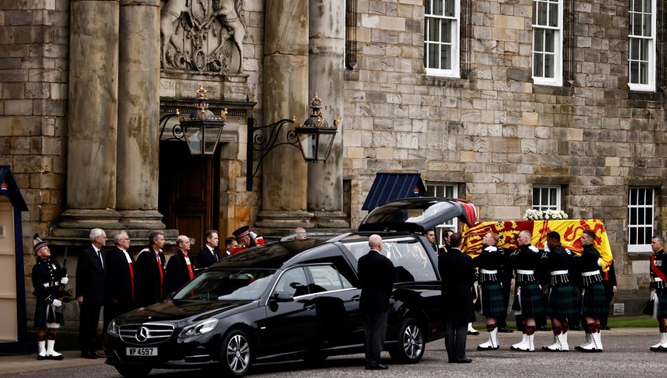 Petugas membawa peti jenazah mendiang Ratu Elizabeth II Inggris yang ditutupi dengan bendera Royal Standard of Scotland saat tiba di Istana Holyroodhouse, Edinburgh, Skotlandia, Minggu (11/9/2022). [ALKIS KONSTANTINIDIS / POOL / AFP]