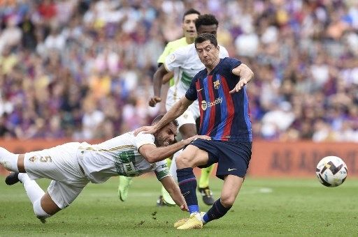 Pemain Barcelona Robert Lewandowski dilanggar pemain Elche dalam pertandingan Liga Spanyol di Camp Nou, Sabtu (17/9/2022). [AFP]