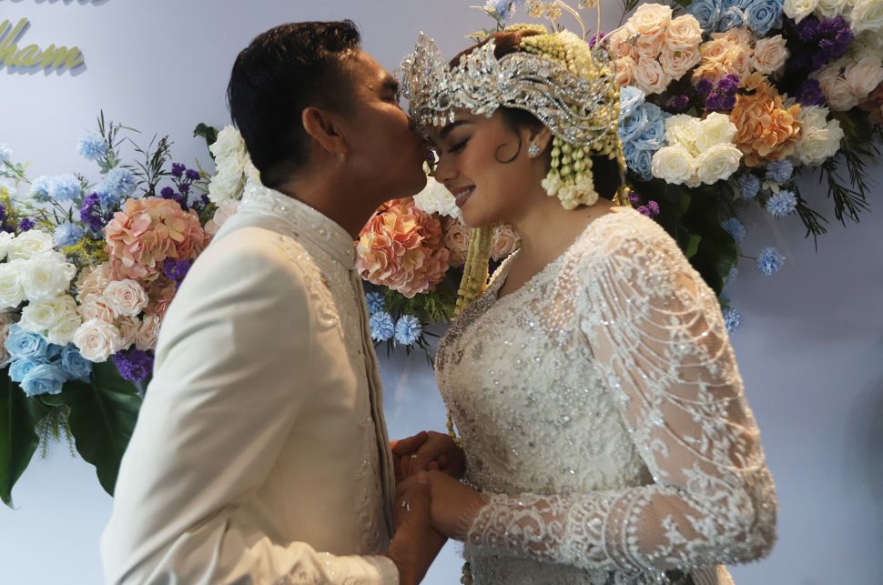 Suamai Catherine Wilson mencium istrinya Catherine Wilson usai akad nikah di Jakarta, Sabtu (1/1). [Suara.com/Oke Atmaja]