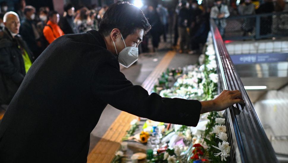 Seorang pria meninggalkan pesan belasungkawa sebagai penghormatan kepada para korban dalam tragedi Itaewon di luar stasiun kereta bawah tanah Itaewon, Seoul, Korea Selatan, Minggu (30/10/2022). [Anthony WALLACE / AFP]