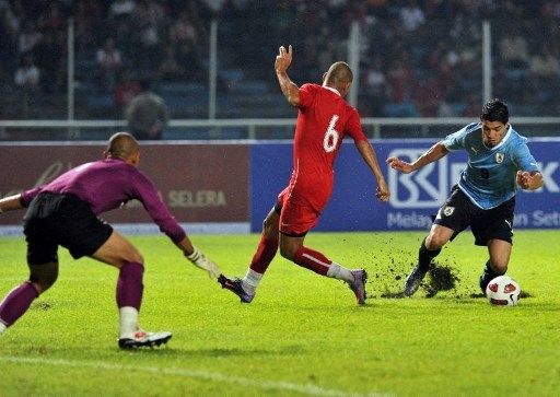 Pemain Uruguay Luis Suarez dijatuhkan Nova Arianto saat berusaha menjebol gawang Indonesia yang dikawal Markus Horison dalam pertandingan persahabatan di SUGBK, Jakarta, pada 8 Oktober 2010. [AFP] 