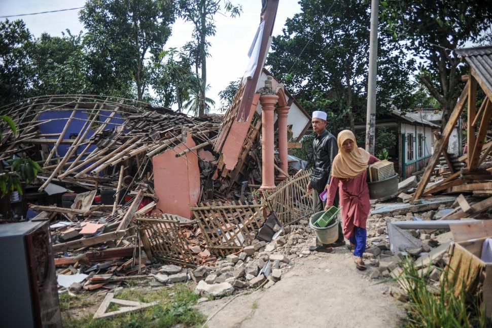 Warga melintas di depan rumah yang roboh akibat gempa di Kampung Selakawung Tengah, Kabupaten Cianjur, Jawa Barat, Selasa (22/11/2022). [ANTARA FOTO/Raisan Al Farisi/pras].