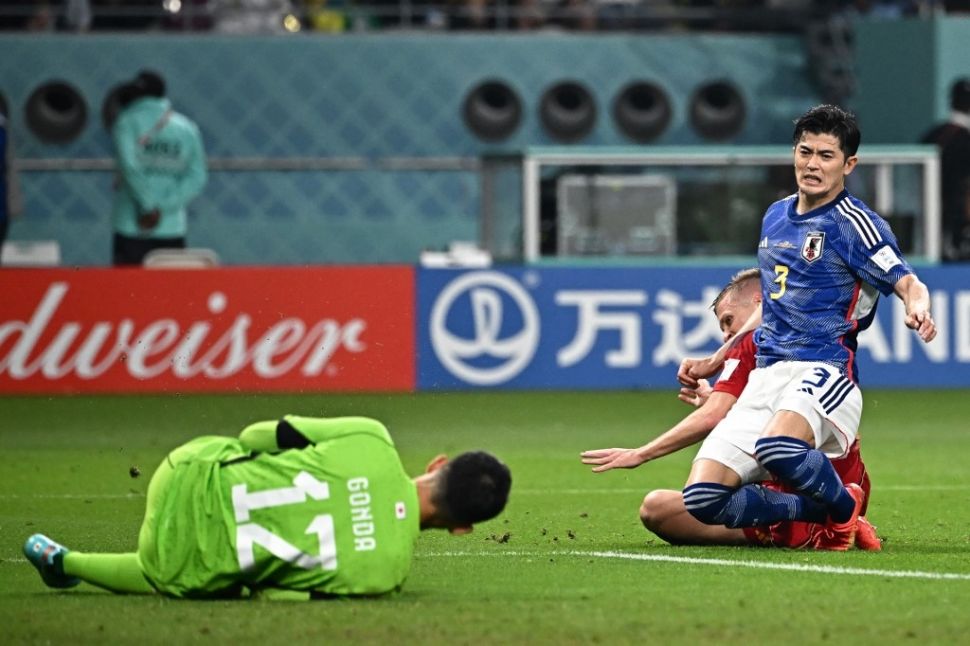 Penyerang Timnas Spanyol #21 Dani Olmo (tengah) melepaskan tembakannya ke gawang kiper Jepang #12 Shuichi Gonda (Kiri) melewati bek Jepang #03 Shogo Taniguchi selama matchday ketiga Grup E Piala Dunia 2022 antara Jepang vs Spanyol di Stadion Internasional Khalifa di Doha pada 1 Desember 2022.Anne-Christine POUJOULAT / AFP.